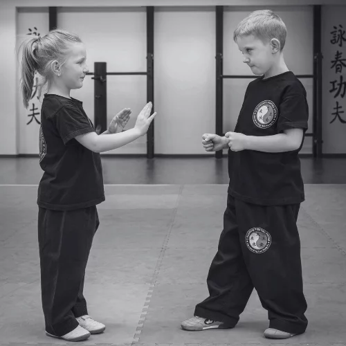 Kinder im Kampfkunst-Training – Mädchen und Junge üben respektvoll im Dojo